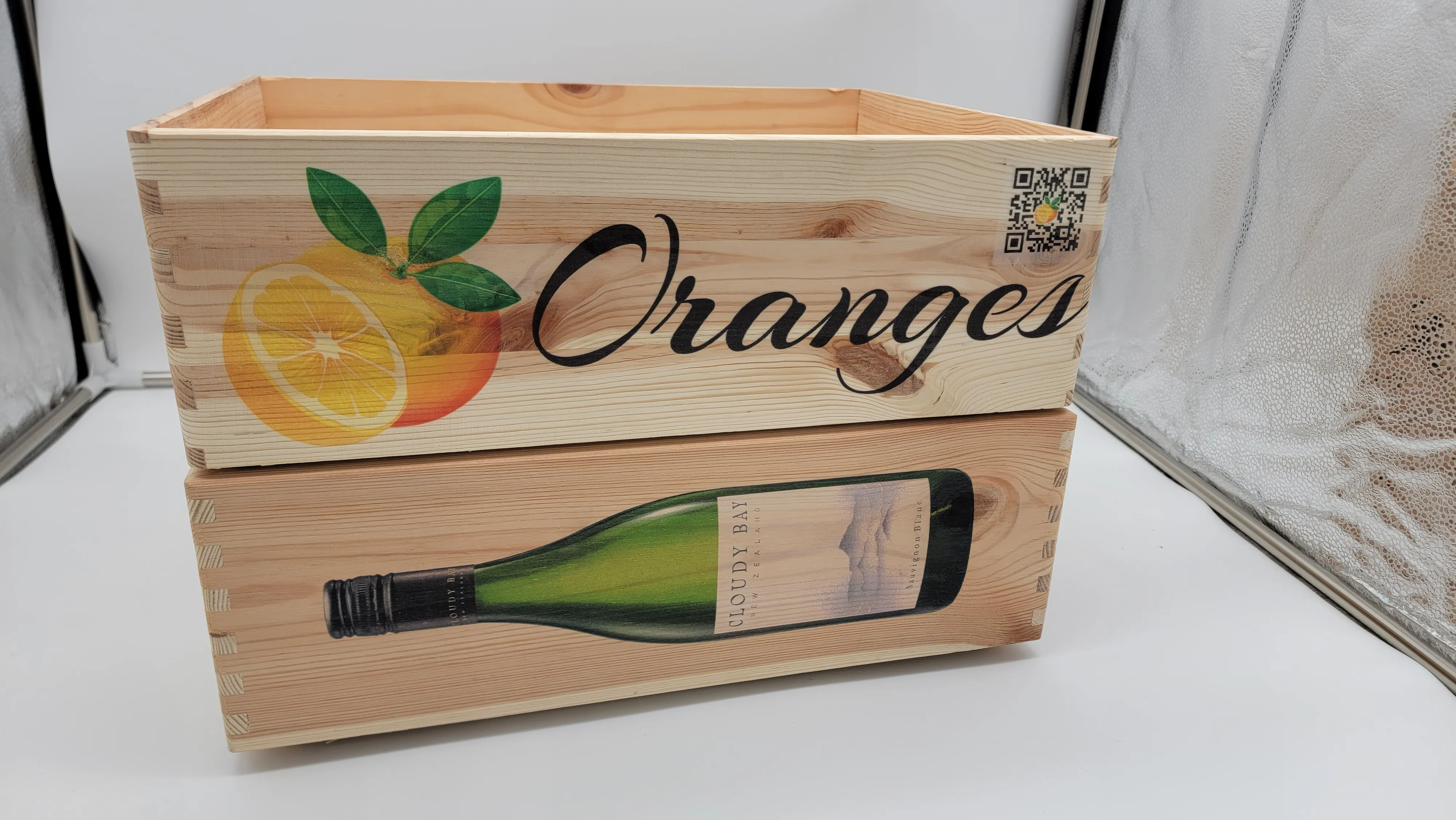 Trälåda med färgtryckta apelsiner, vinflaska och texten Oranges